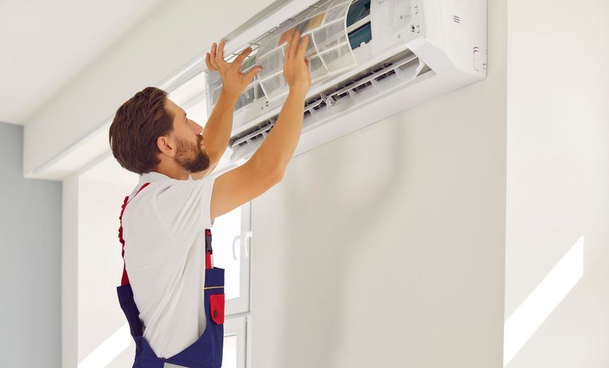 Technician cleaning a wall-mounted air conditioner indoors