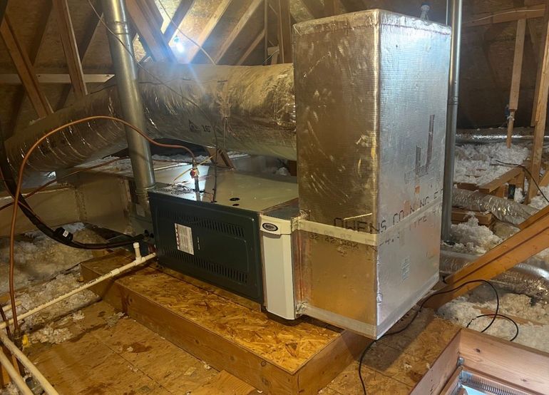 HVAC furnace with silver ductwork in an unfinished attic space