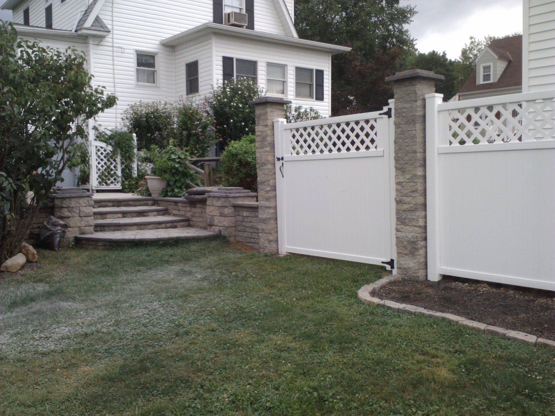 A white fence with a gate in front of a house