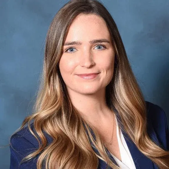 Portrait of a woman in a blue blazer against a gray background