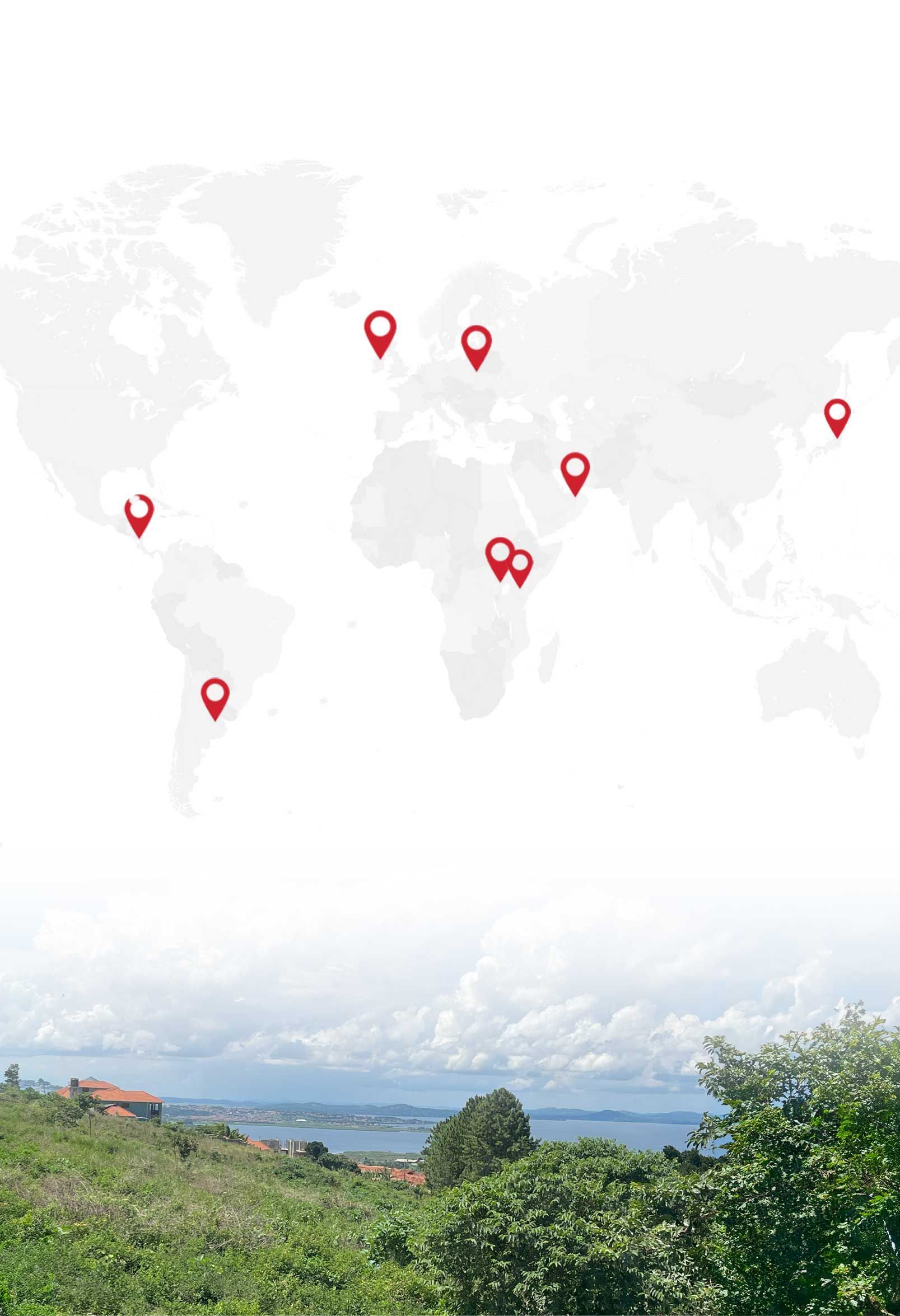 World map with red location pins above a lush green landscape and cloudy sky