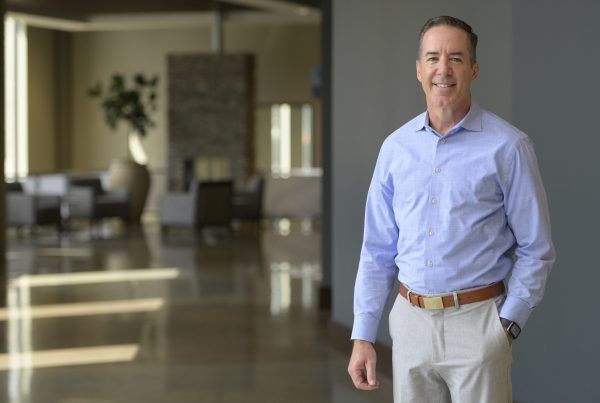 Man in a light blue shirt and khaki pants standing in a modern office lobby