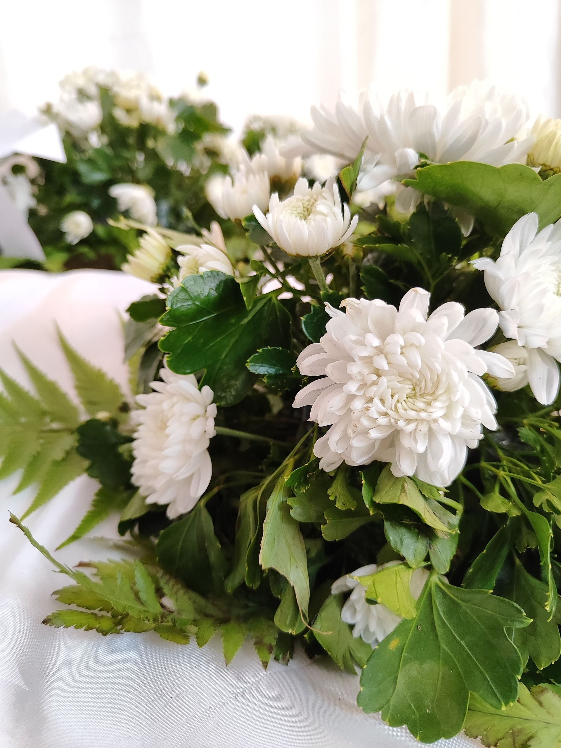 White flowers with green leaves in a bouquet on a light surface