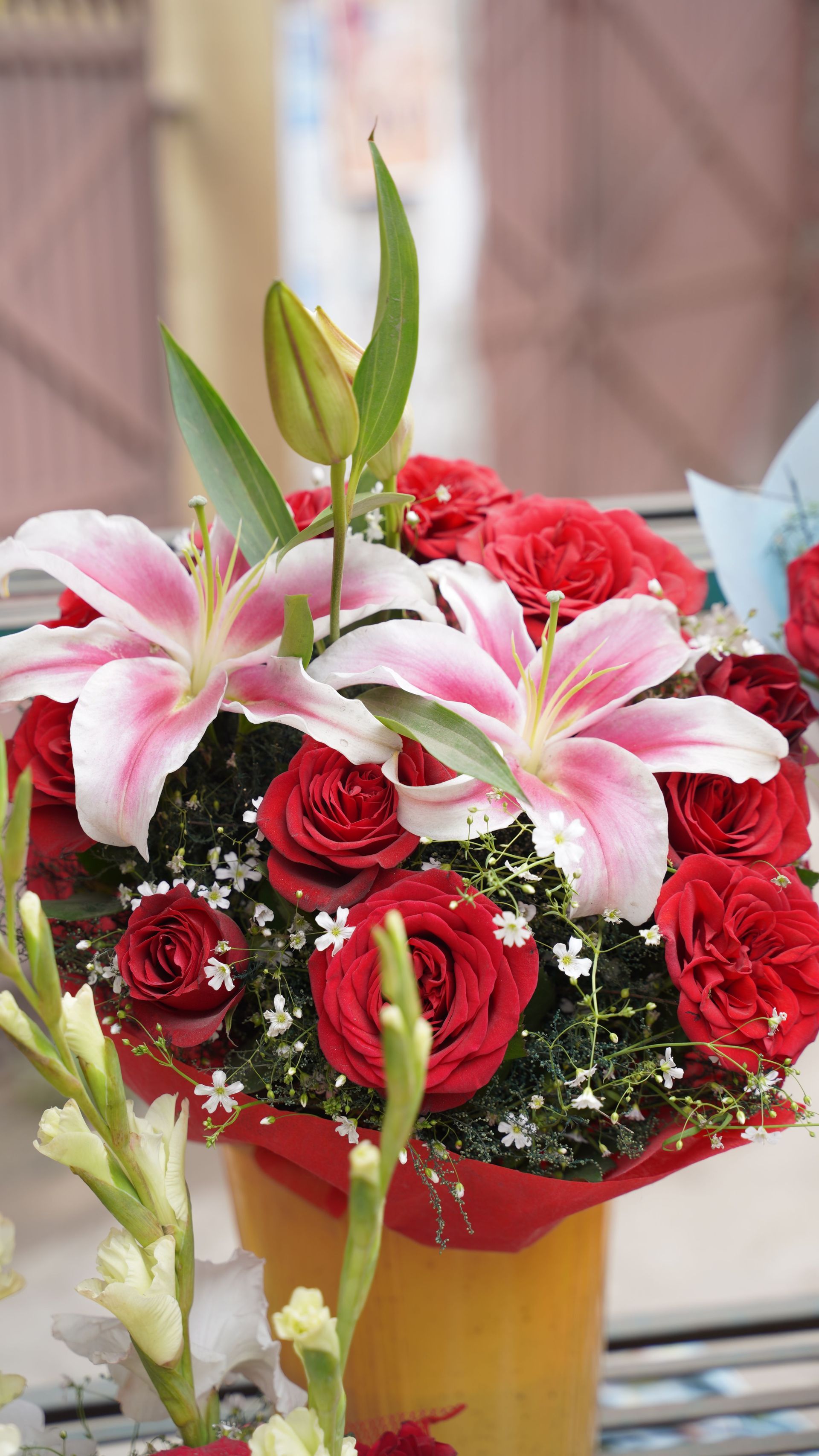 Bouquet of pink lilies and red roses in a gold vase