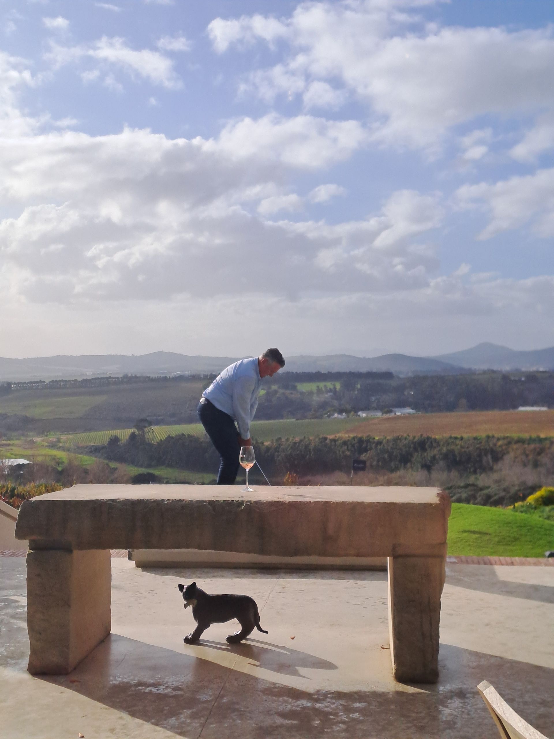 Person hitting golf club, with hills and sky in the background