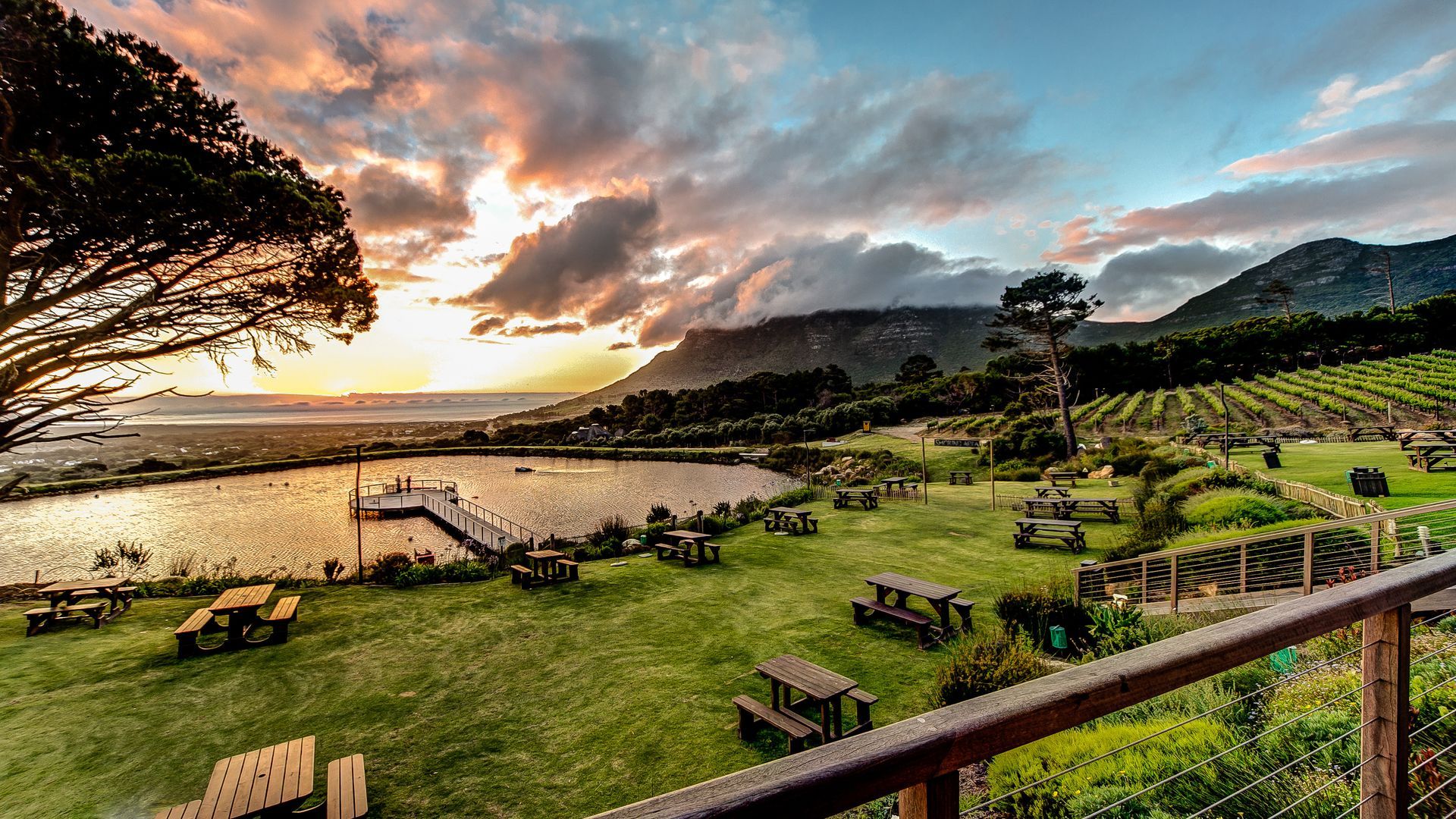 Sunset over a lookout deck with benches, mountains, sea view and dramatic clouds