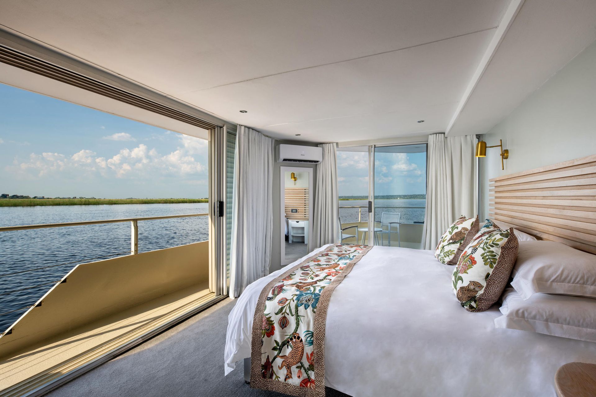 Modern bedroom with large bed and river-view balcony through sliding glass doors