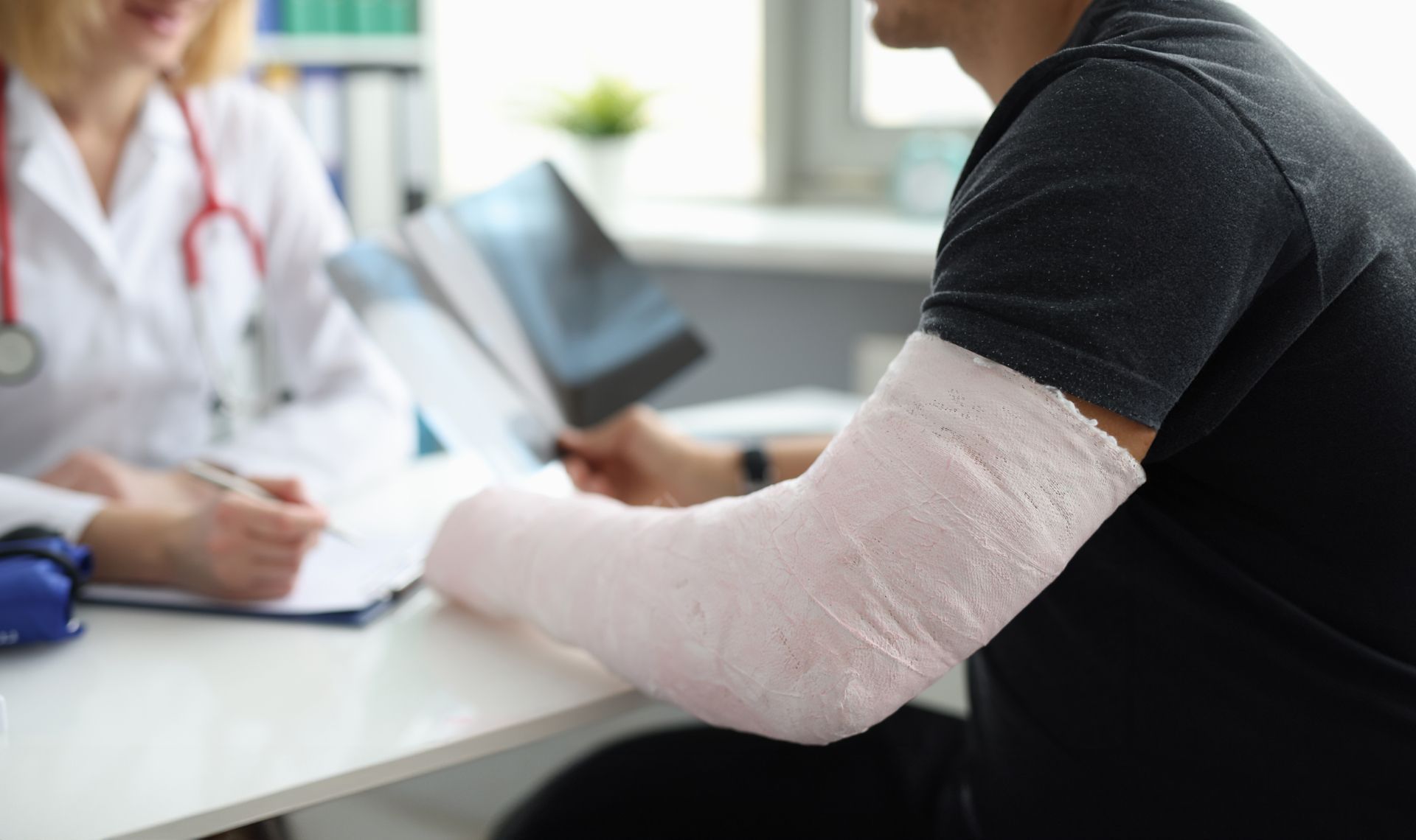 Doctor examining a patient’s bandaged arm in a clinic