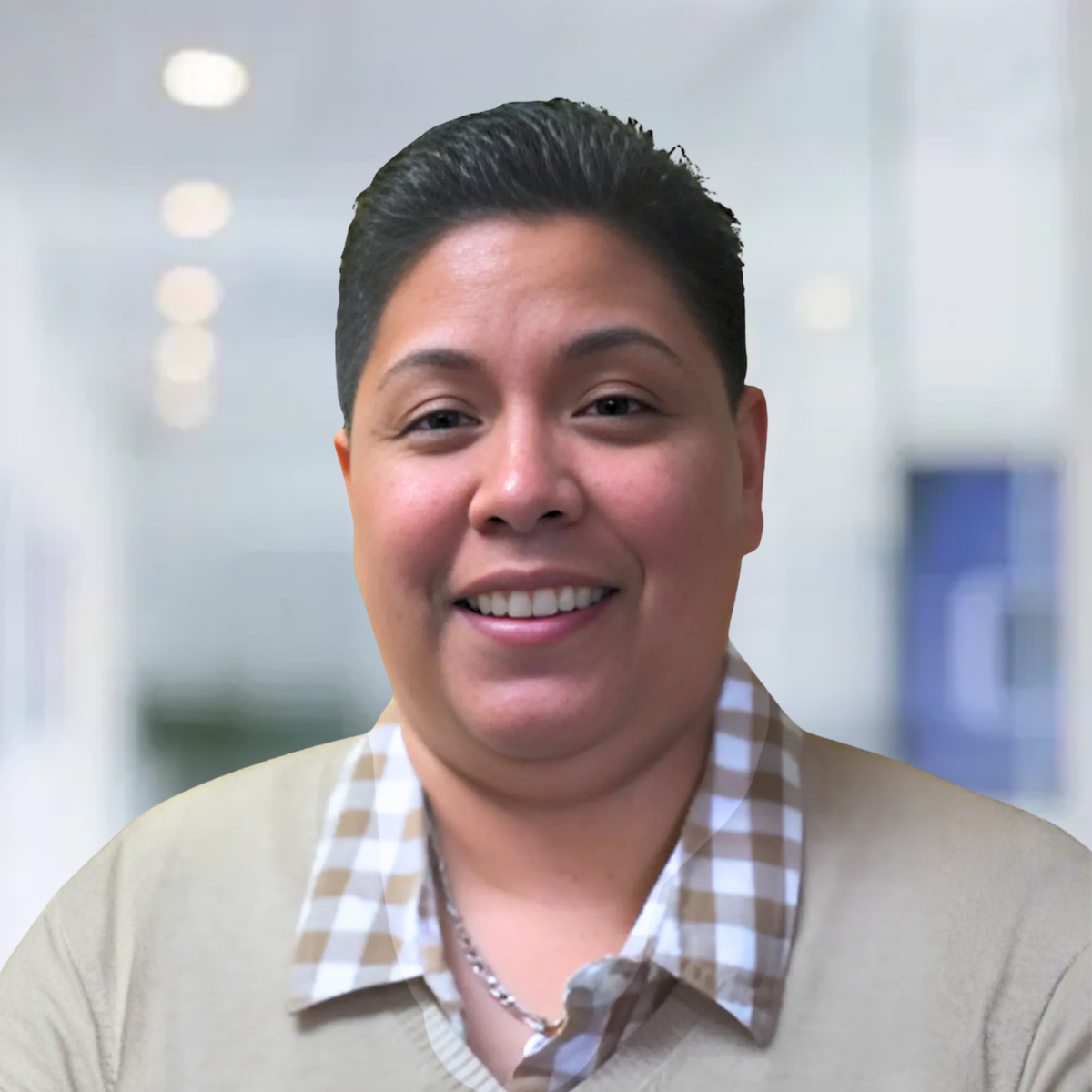 A woman in a tan shirt is smiling for the camera.