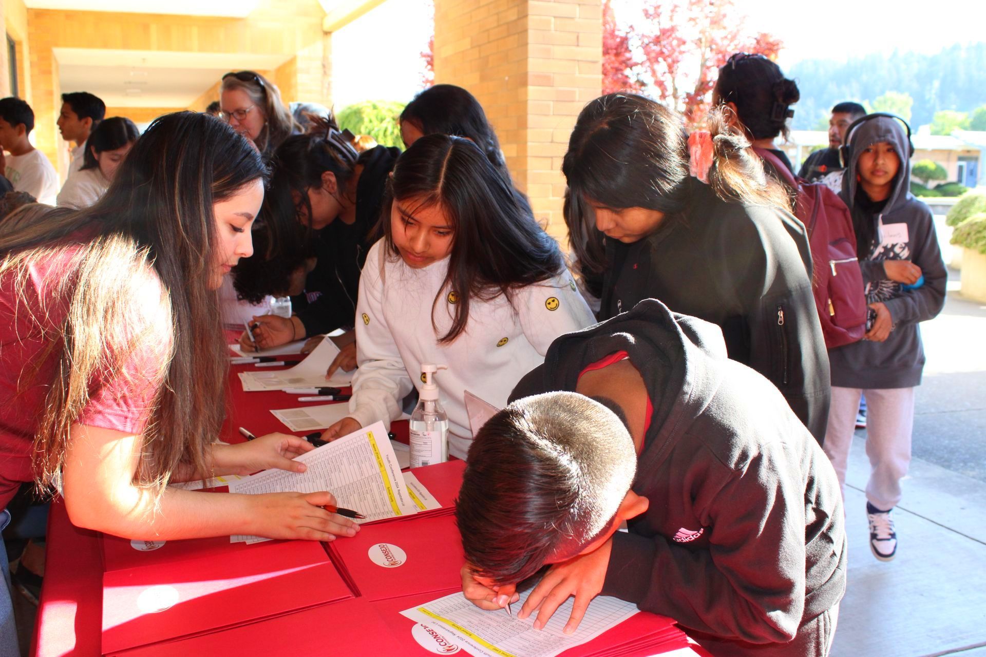 A group of people are standing around a table signing papers.