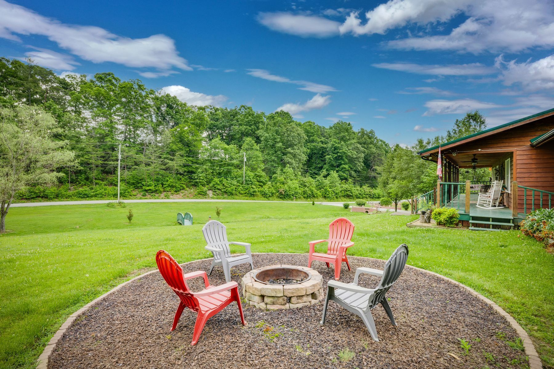 A fire pit in the middle of a lush green field with chairs around it. Greeneville, TN