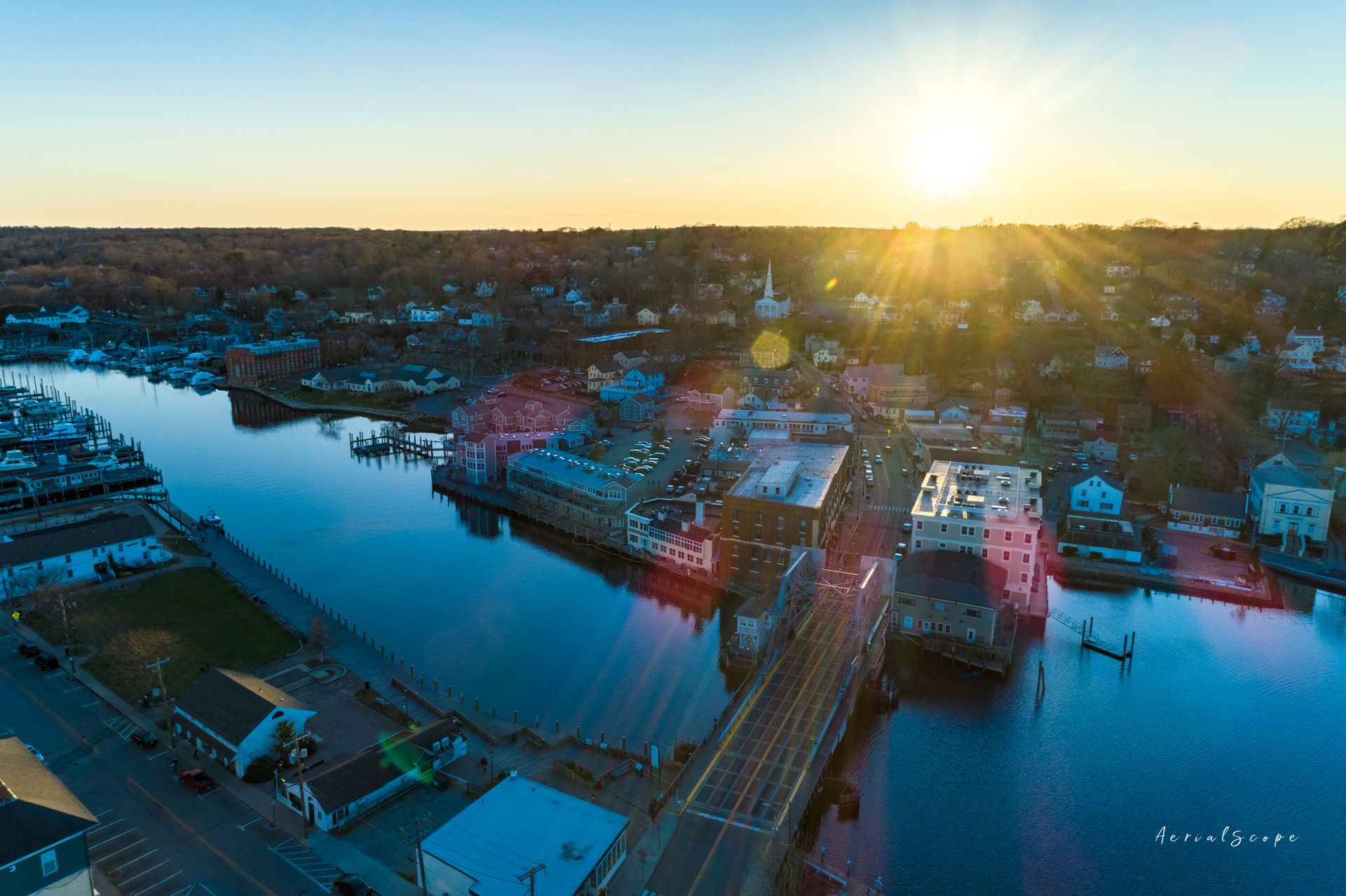 Aerial view of a town with a river running through it at sunset. Golden light reflects on the water.