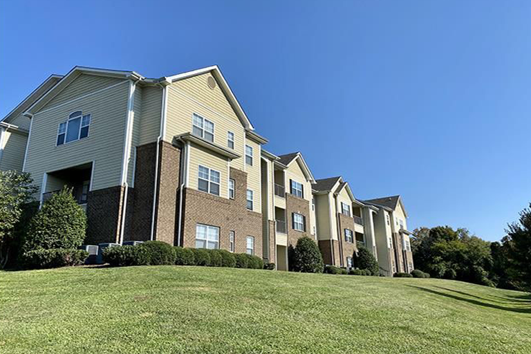 A large apartment building is sitting on top of a lush green hillside. Knoxville, TN