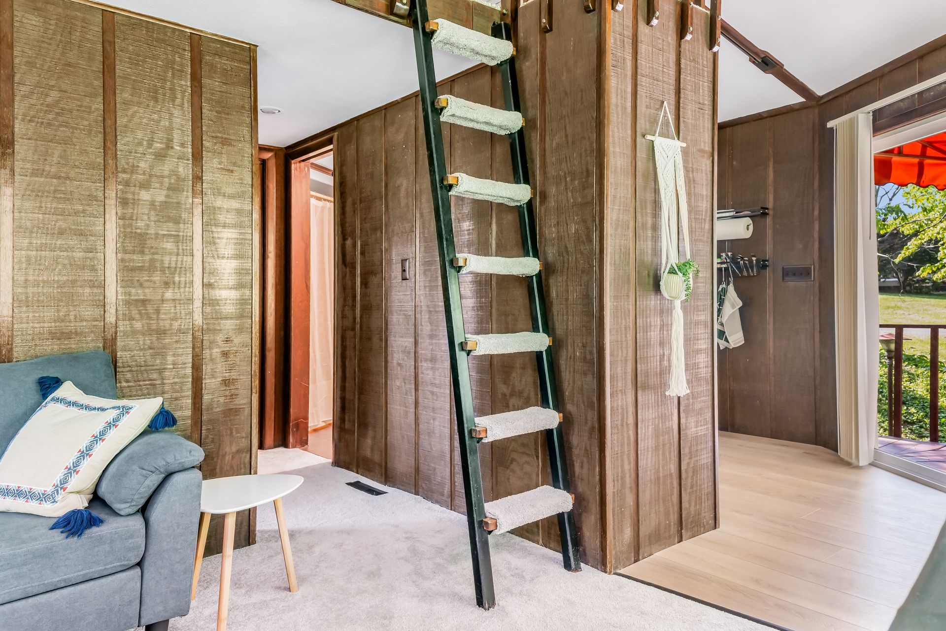 A living room with a couch and a ladder leading to a loft.