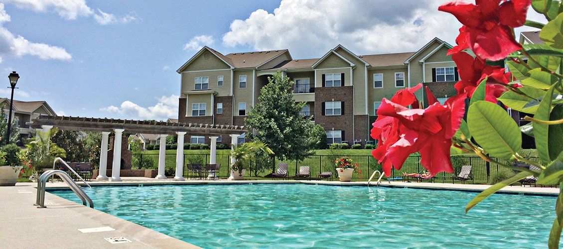 A large swimming pool with a building in the background and flowers in the foreground.