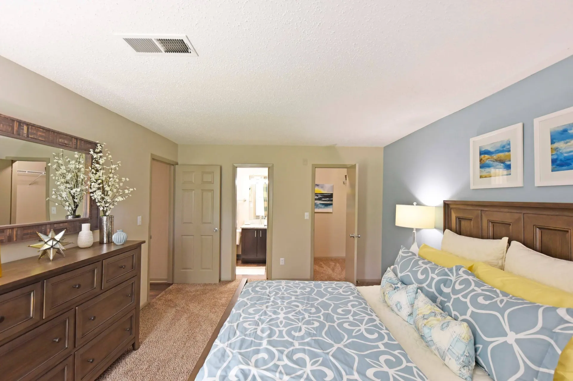 A modern fully furnished bedroom with a large bed , dresser and mirror in West Knoxville, TN