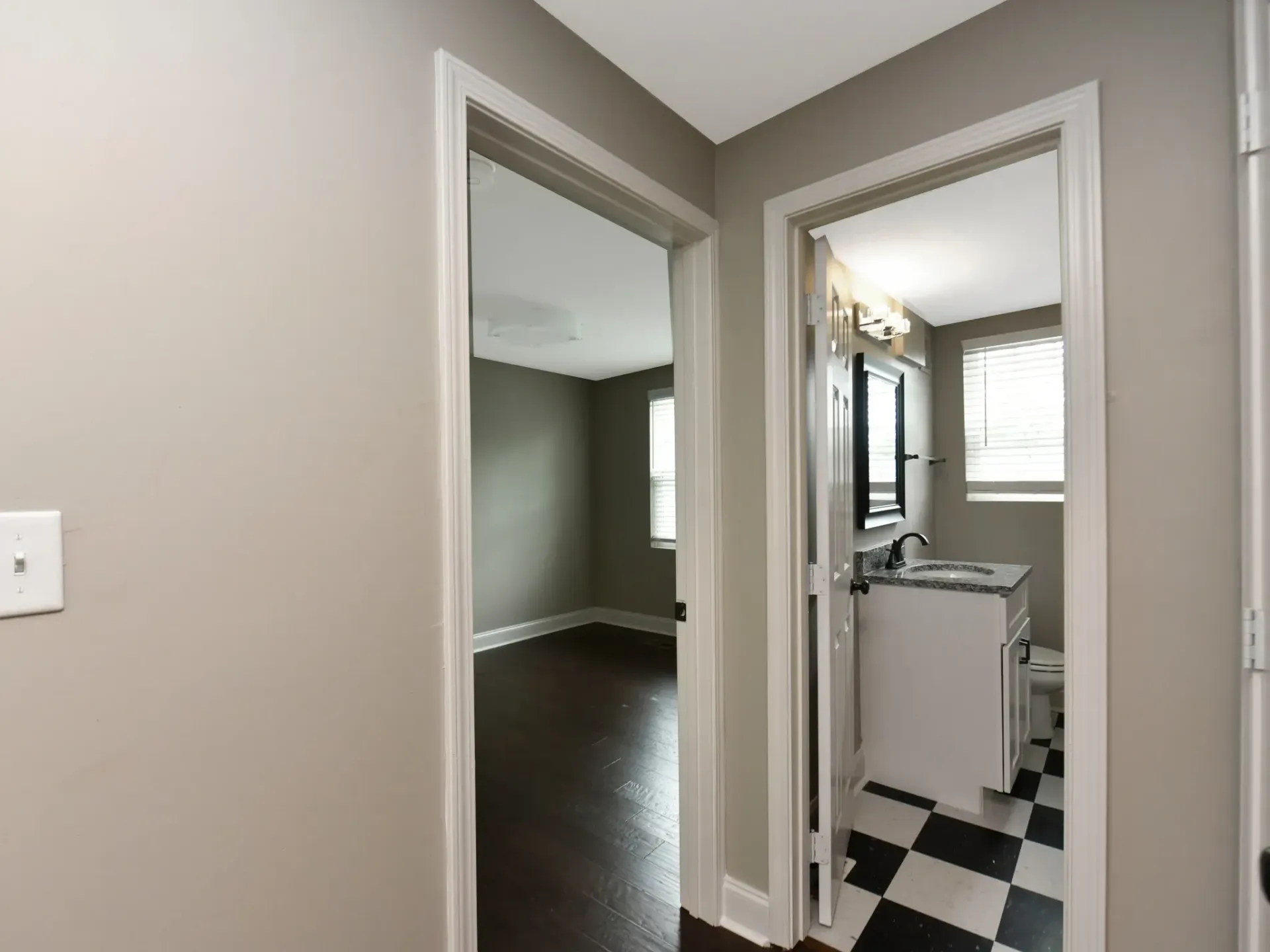 A hallway leading to a bathroom with a checkered floor.
