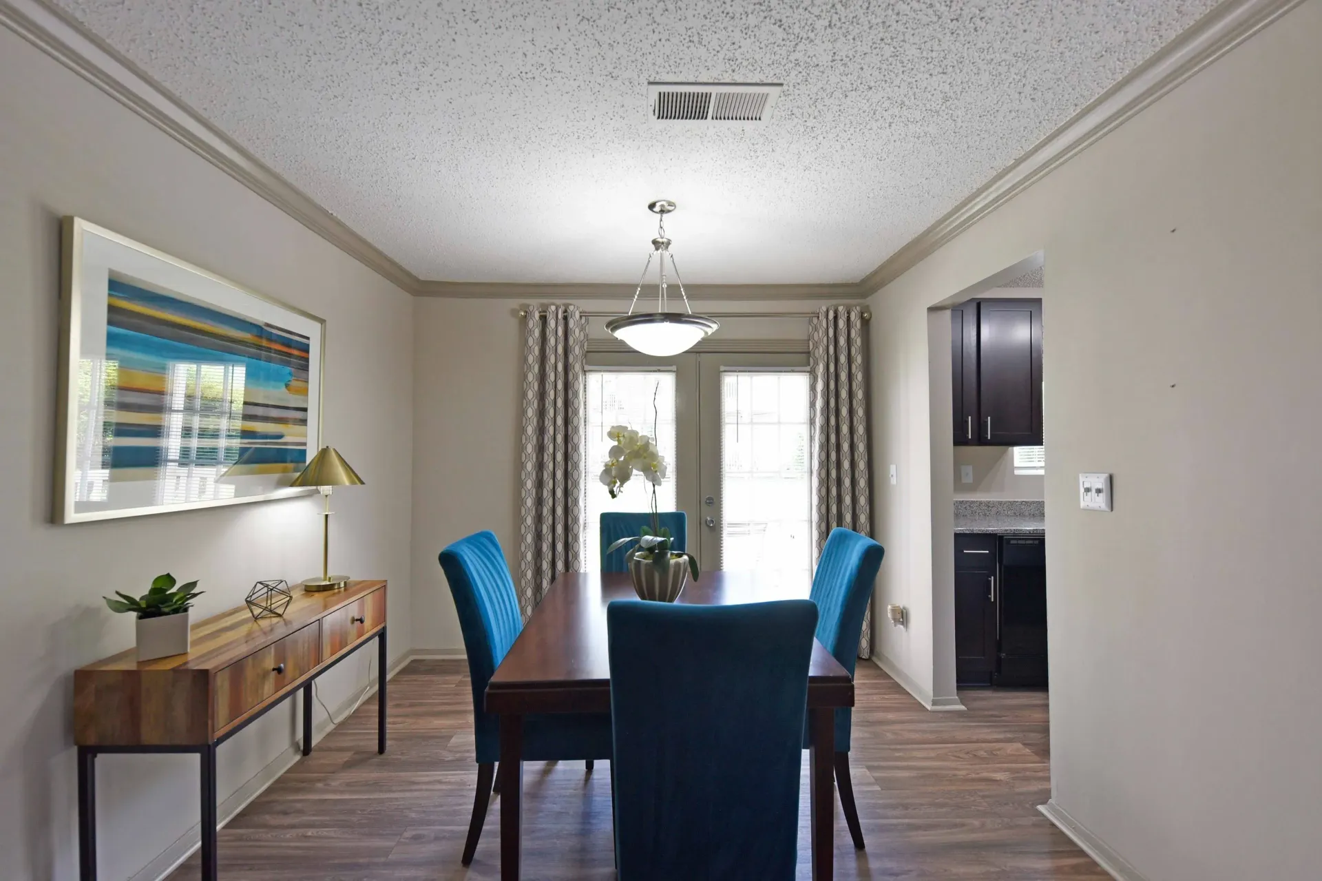 A modern fully furnished dining room with a table and chairs and a painting on the wall in West Knoxville, TN