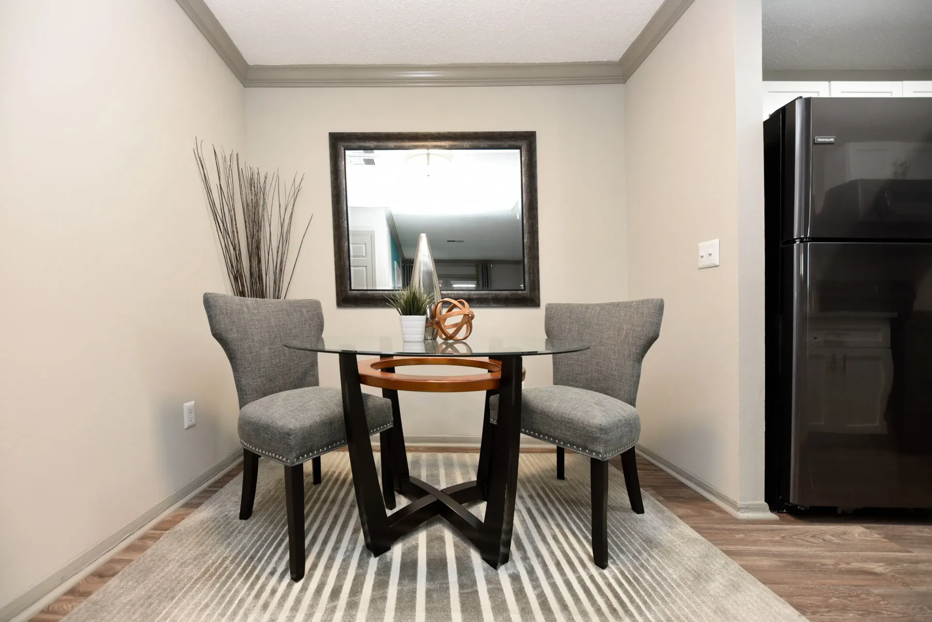 A modern furnished dining room with a table and chairs and a black refrigerator in West Knoxville, TN