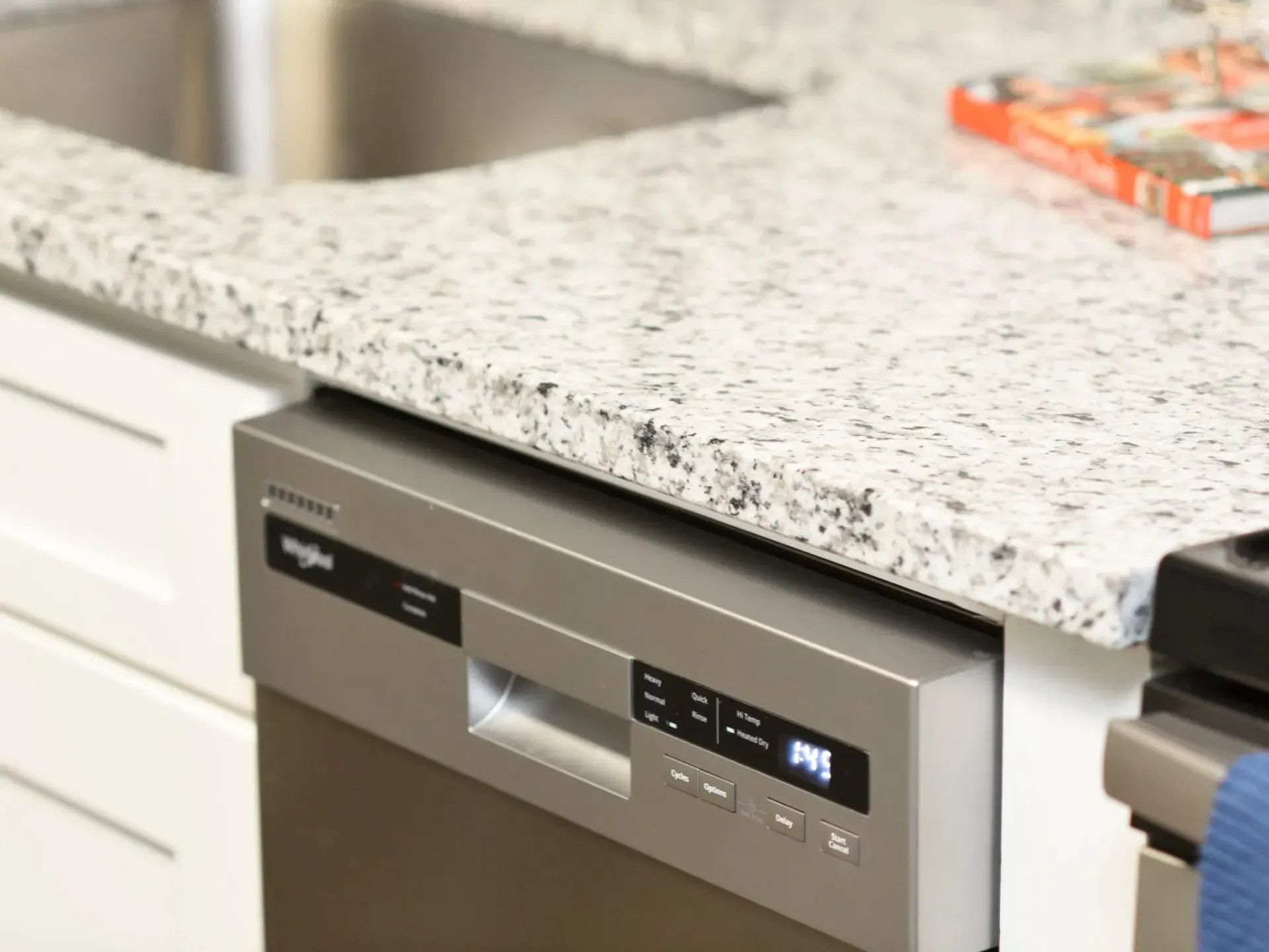 A stainless steel dishwasher is sitting under a granite counter in West Knoxville, TN