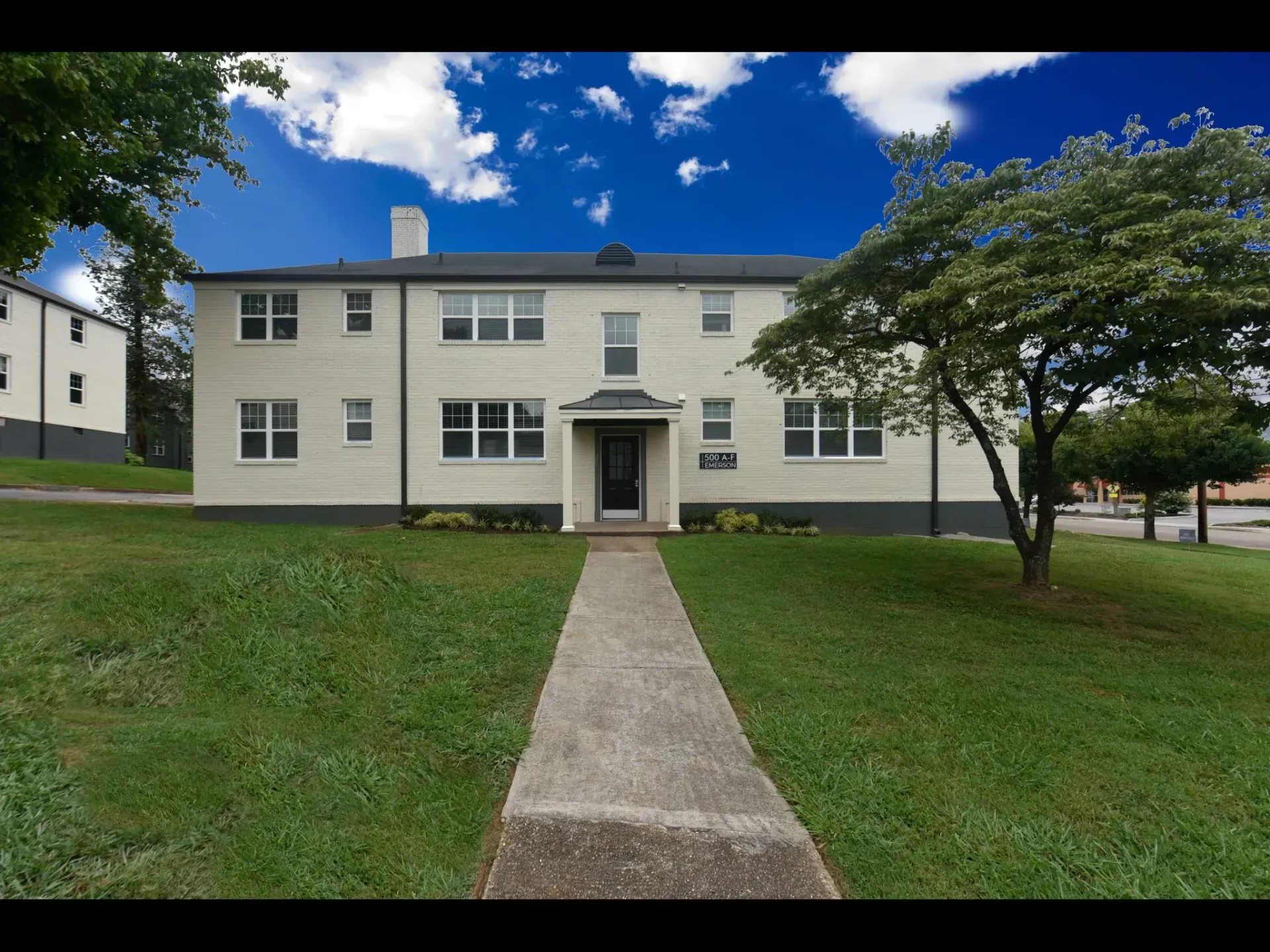 A white house with a concrete walkway leading to it