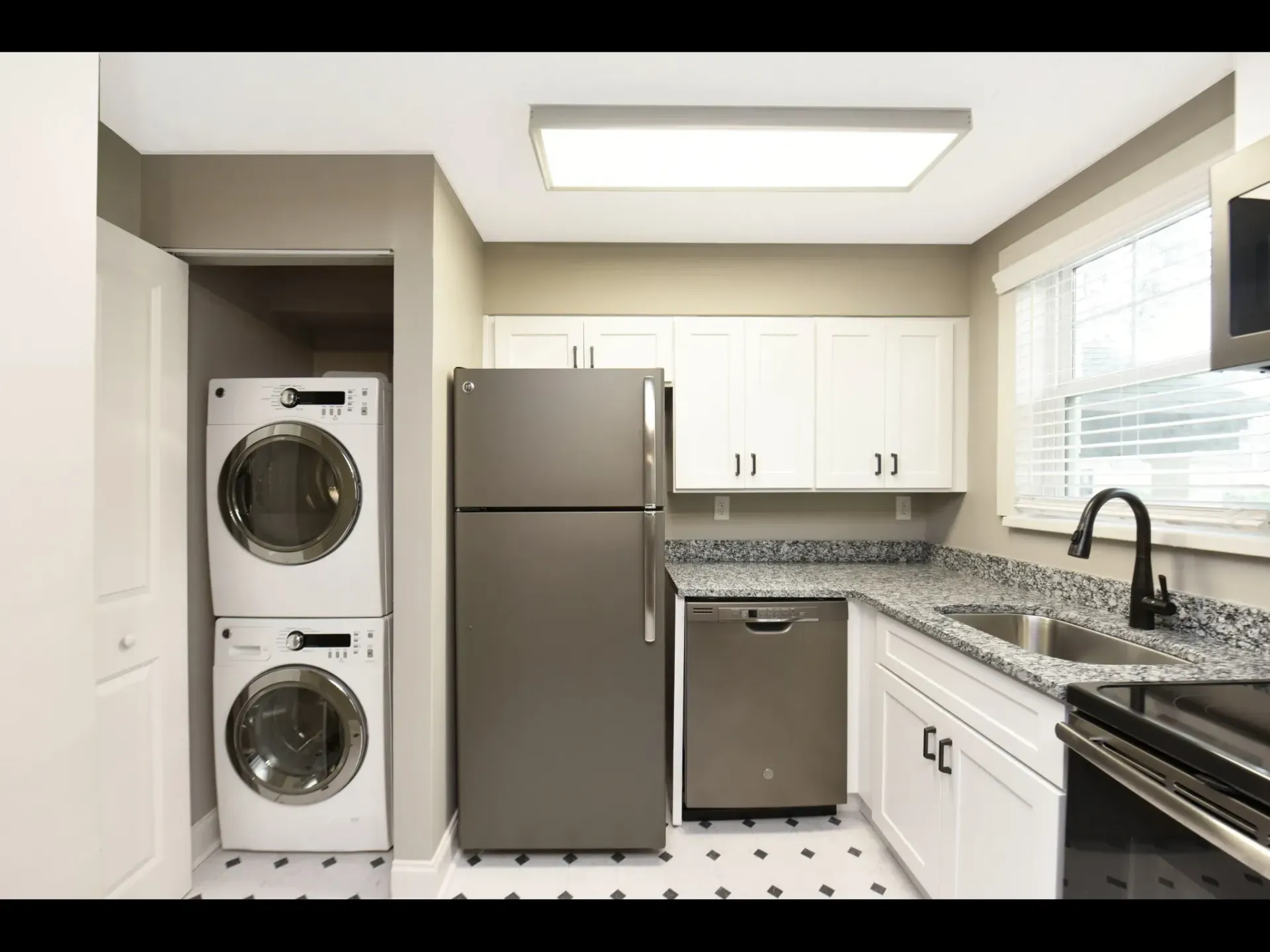 A kitchen with a washer and dryer stacked on top of each other.
