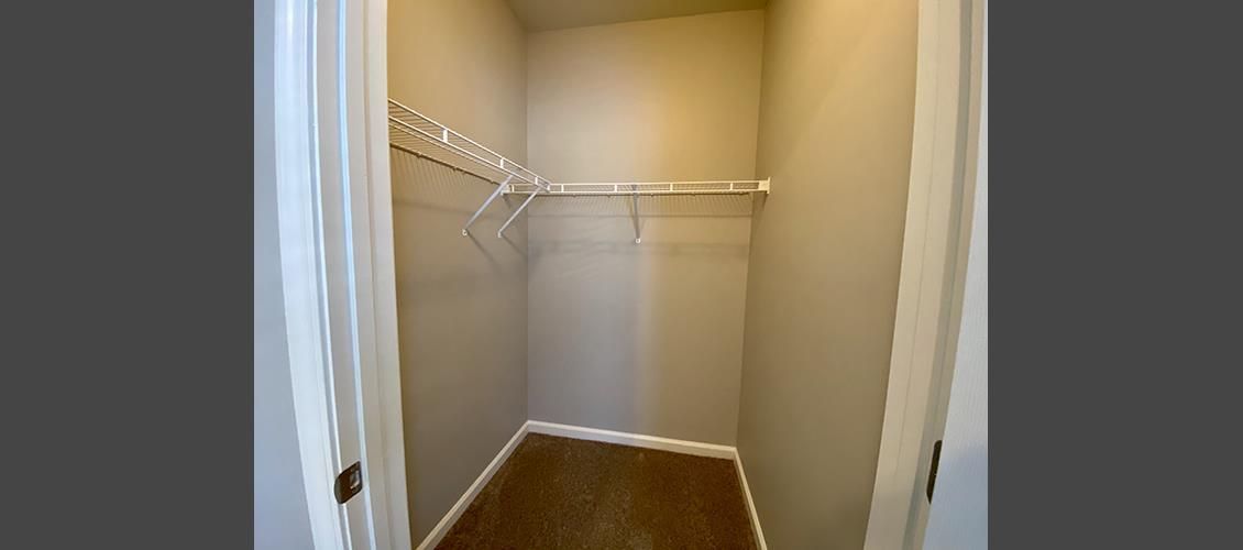 An empty walk in closet with hardwood floors and clothes racks.