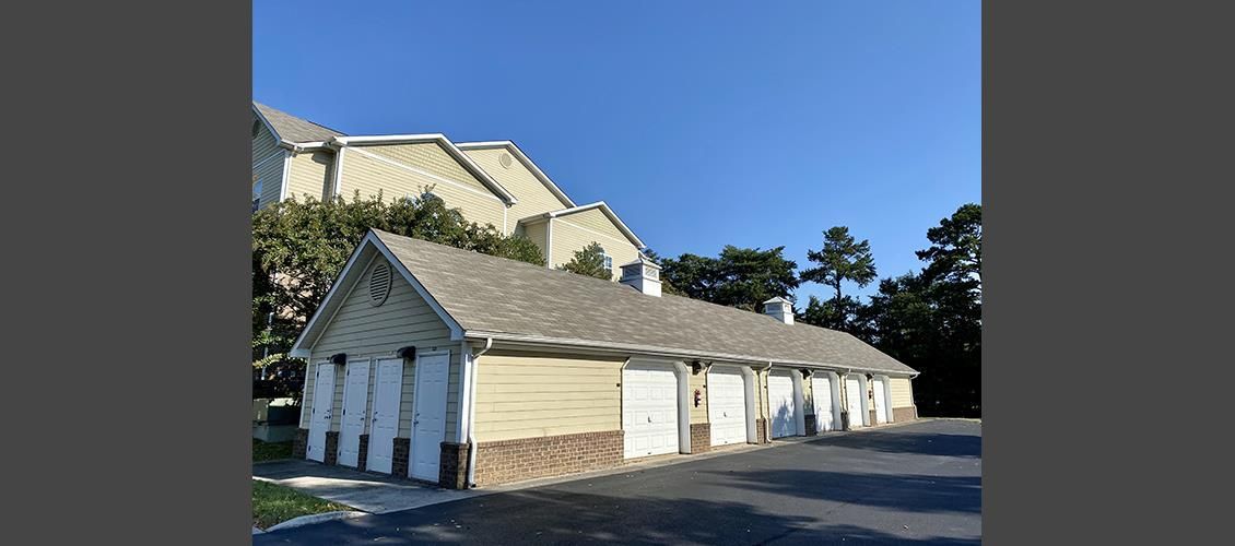 A row of garages next to a building with a blue sky in the background.