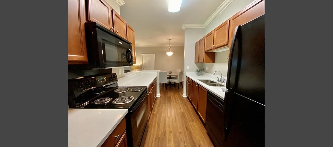 A kitchen with a stove , refrigerator , microwave and sink.