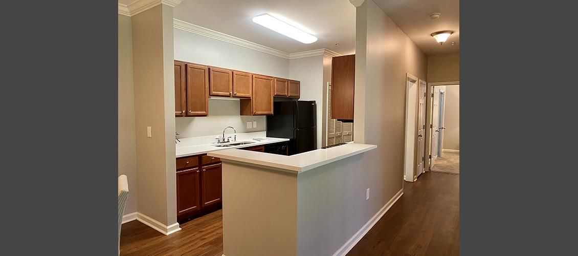 A kitchen with wooden cabinets and a refrigerator in a house.