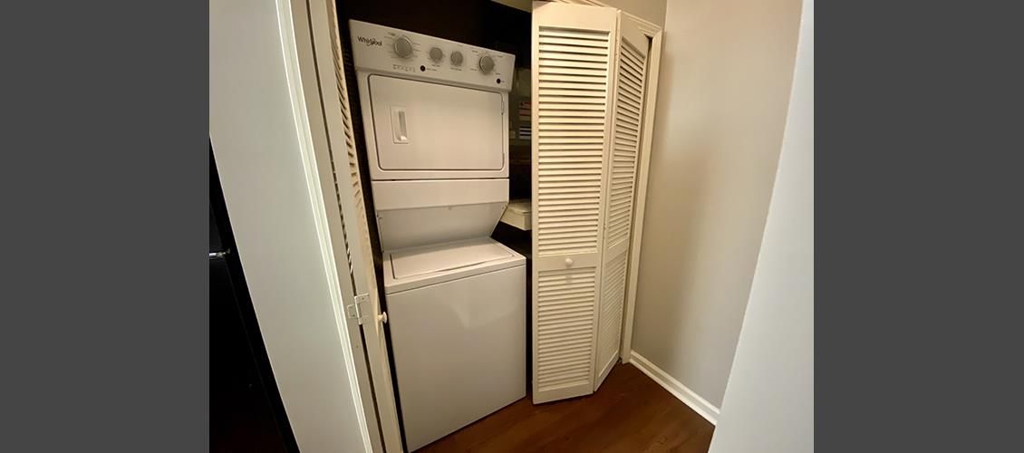 A washer and dryer are stacked on top of each other in a closet.