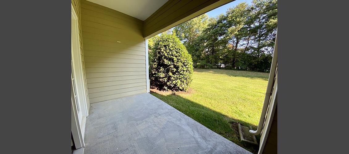 A patio with a view of a grassy field and trees.
