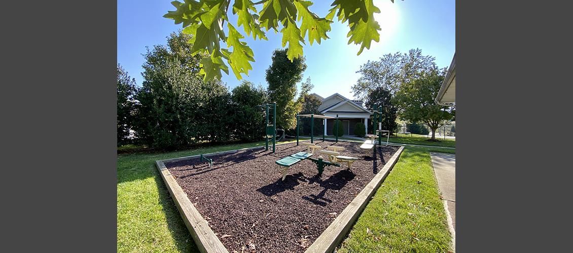 A playground in a park with a gazebo in the background.