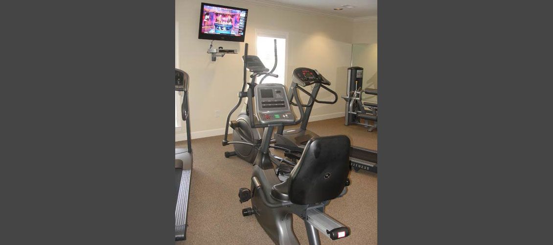 A gym with exercise bikes , treadmills , and a television.