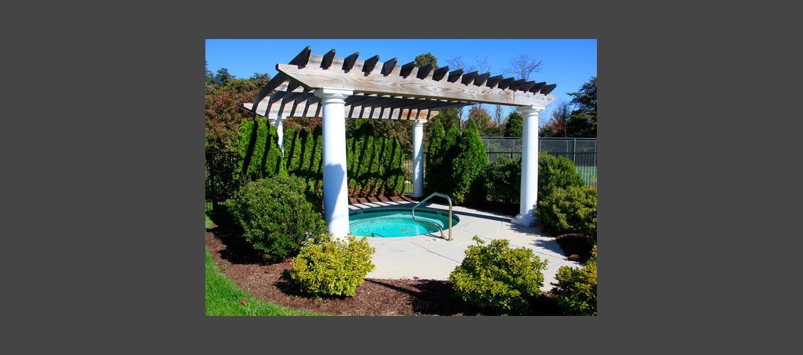 A hot tub under a pergola in a backyard