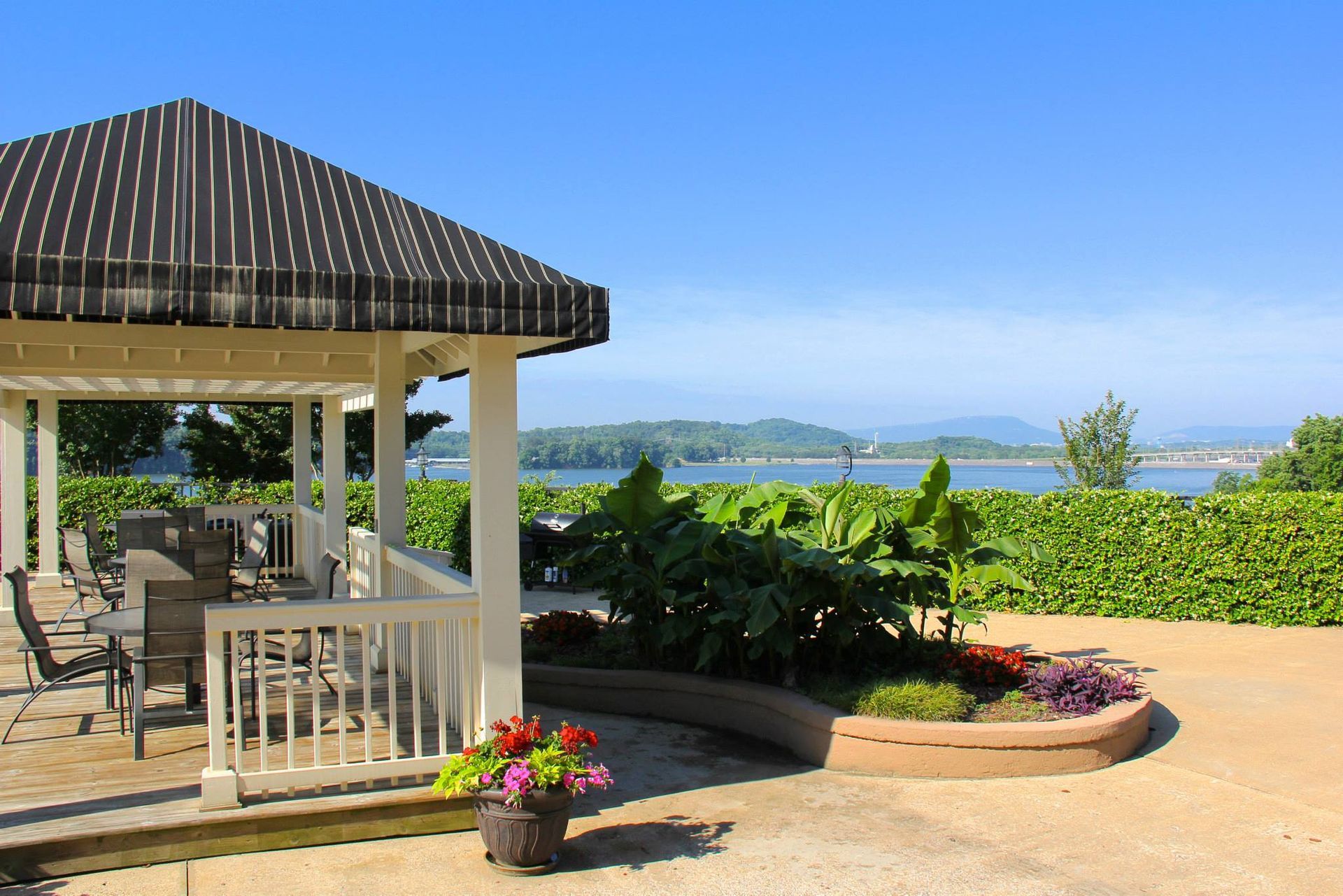 Gazebo with seating, overlooking a body of water and land, on a sunny day.