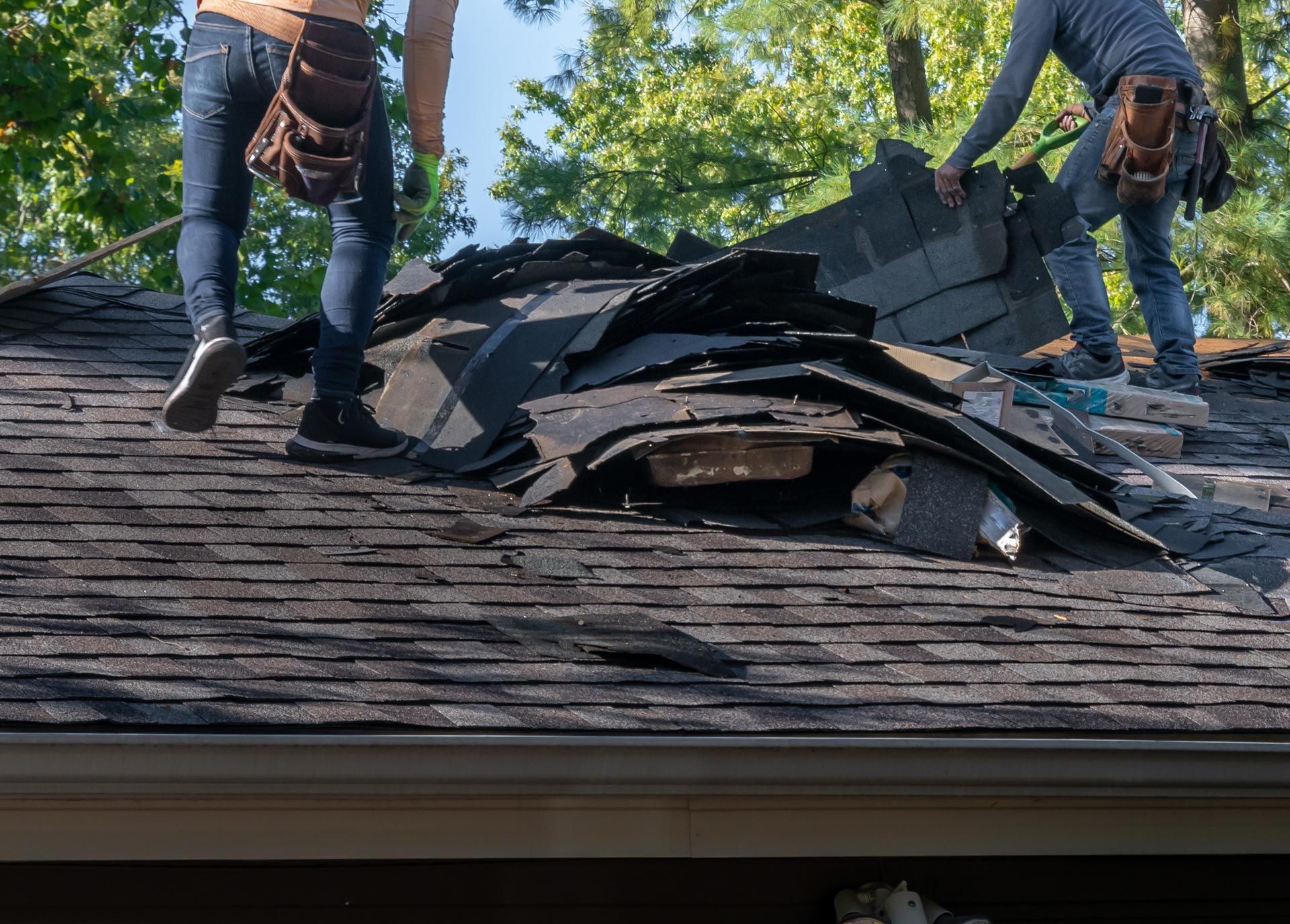 Roof replacement workers removing old shingles during residential repair. Roof replacement workers removing old shingles during residential repair.
