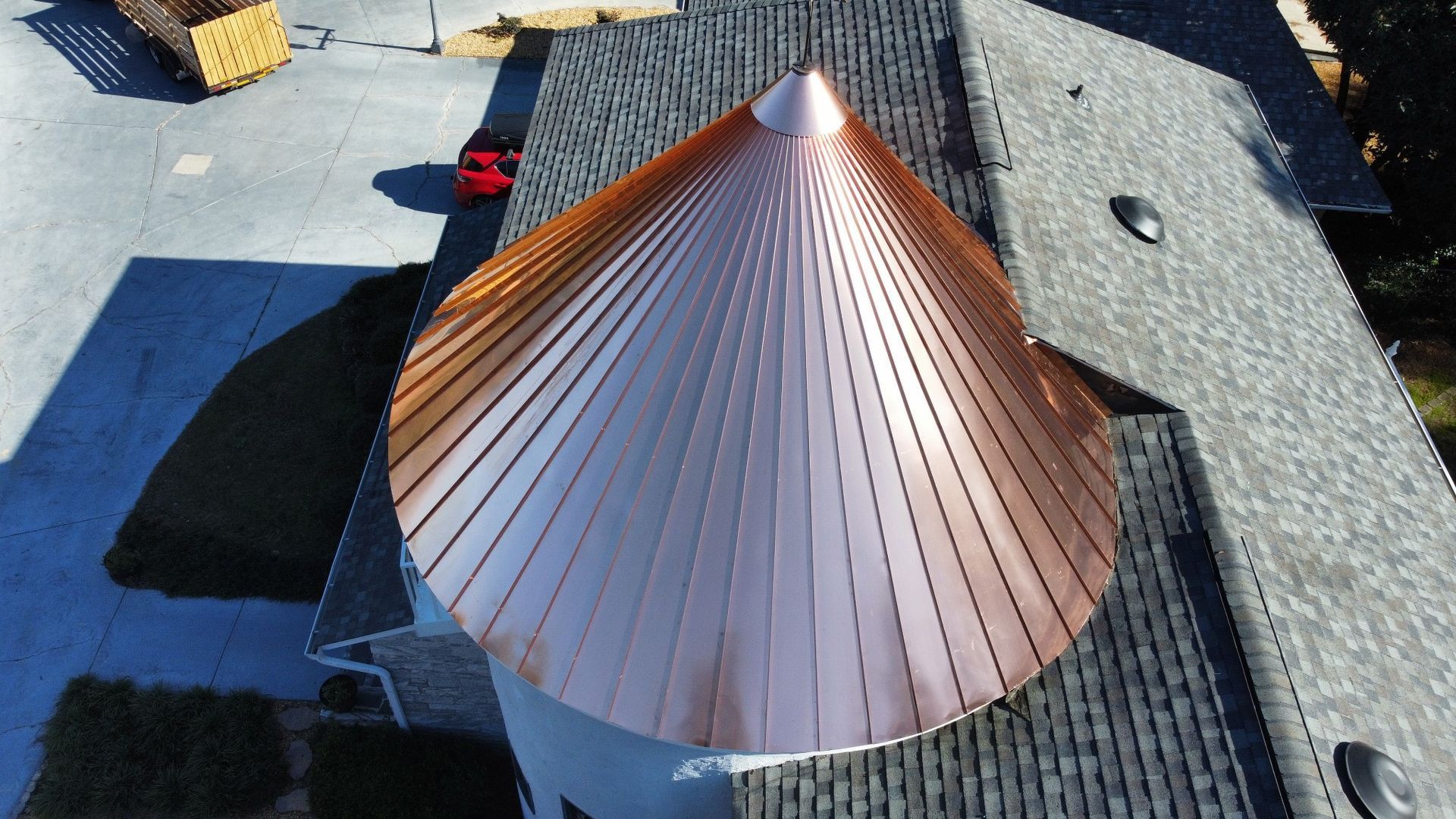 Copper conical roof on a building, seen from above with rooftop gravel and shadows nearby