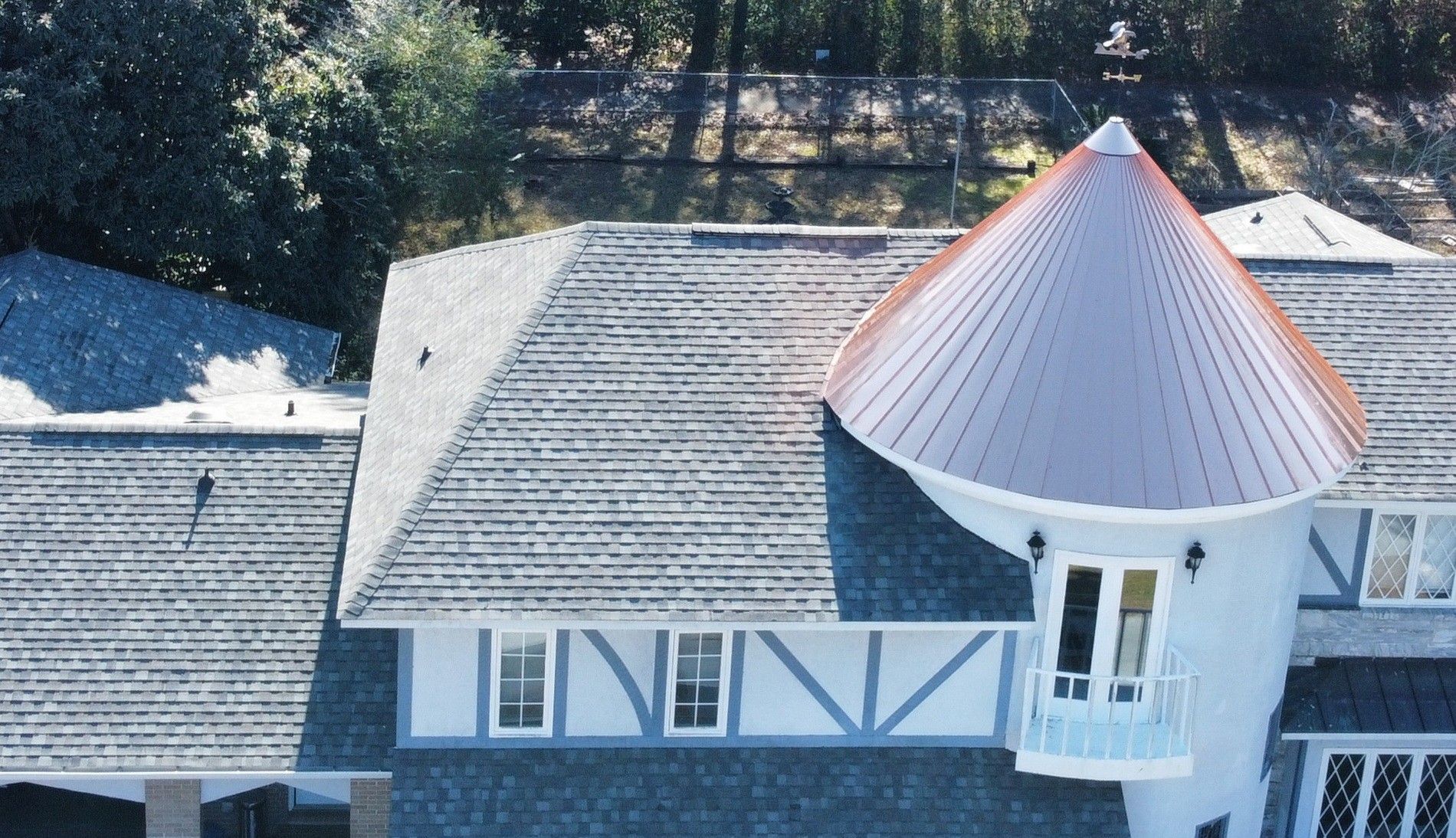 Snowy rooftop with gray shingles and a white turret topped by a copper-colored conical roof