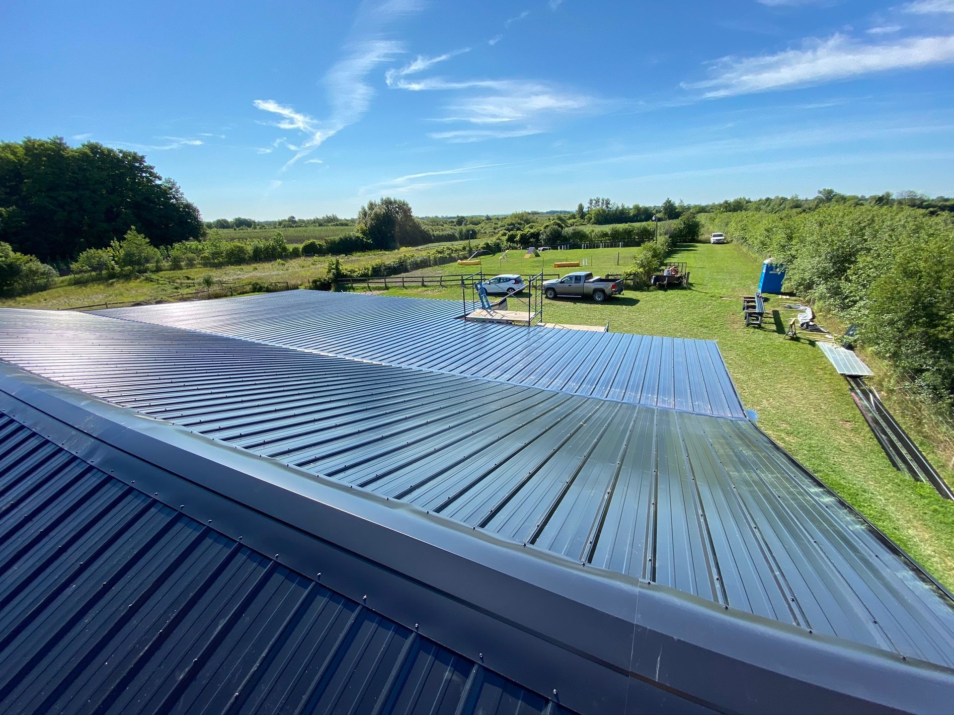 Solar roof panels in a green field with blue sky and countryside hills
