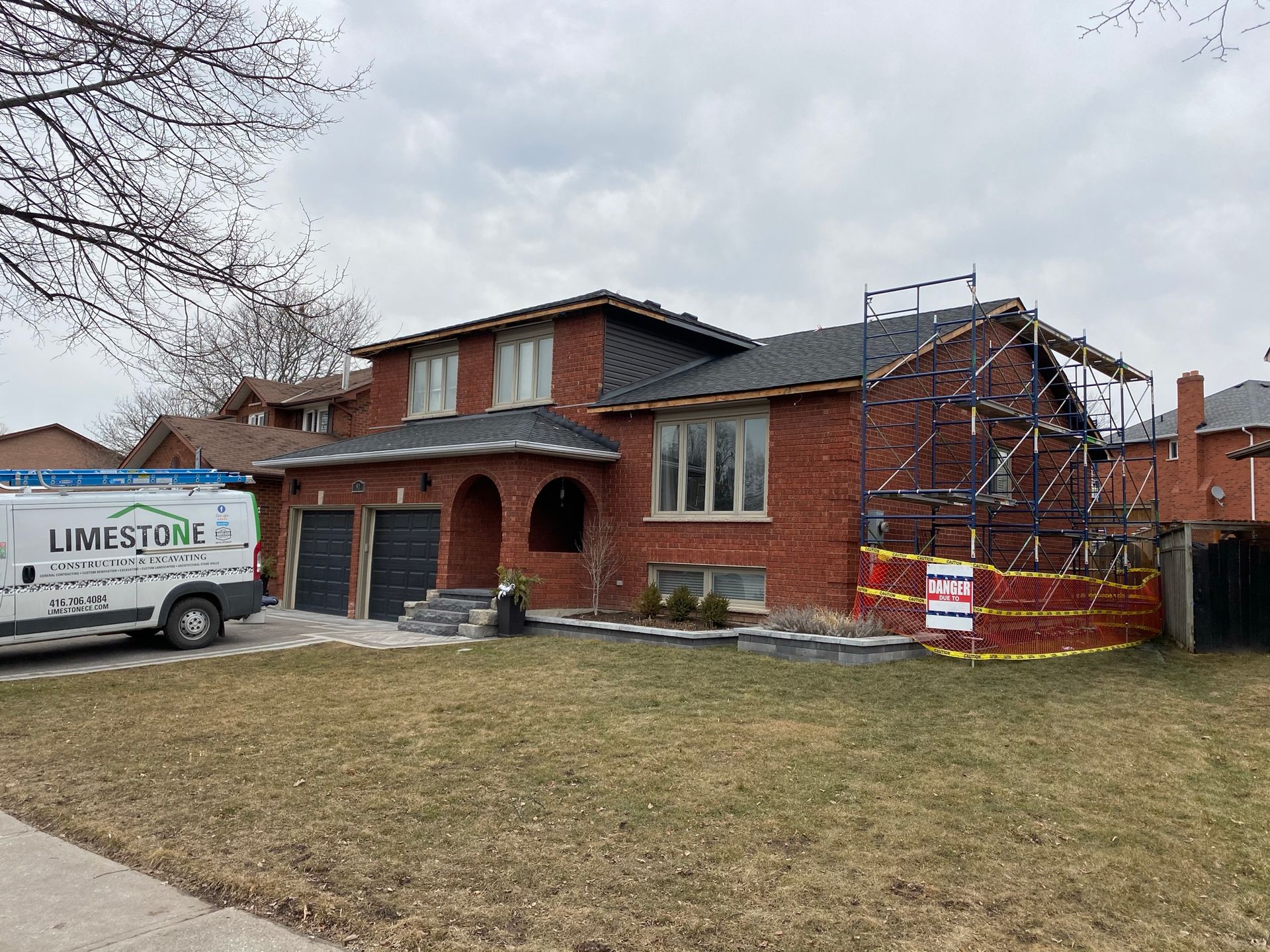 Red-brick house with roof repairs, scaffolding, and a work van parked on the lawn.