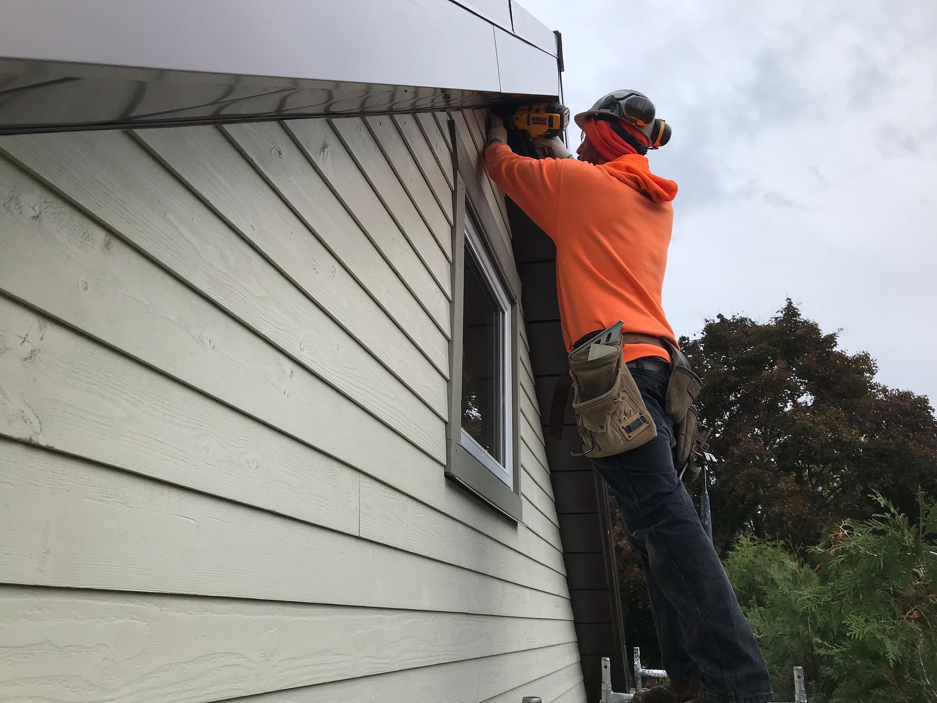 a man is working on the side of a house with a drill