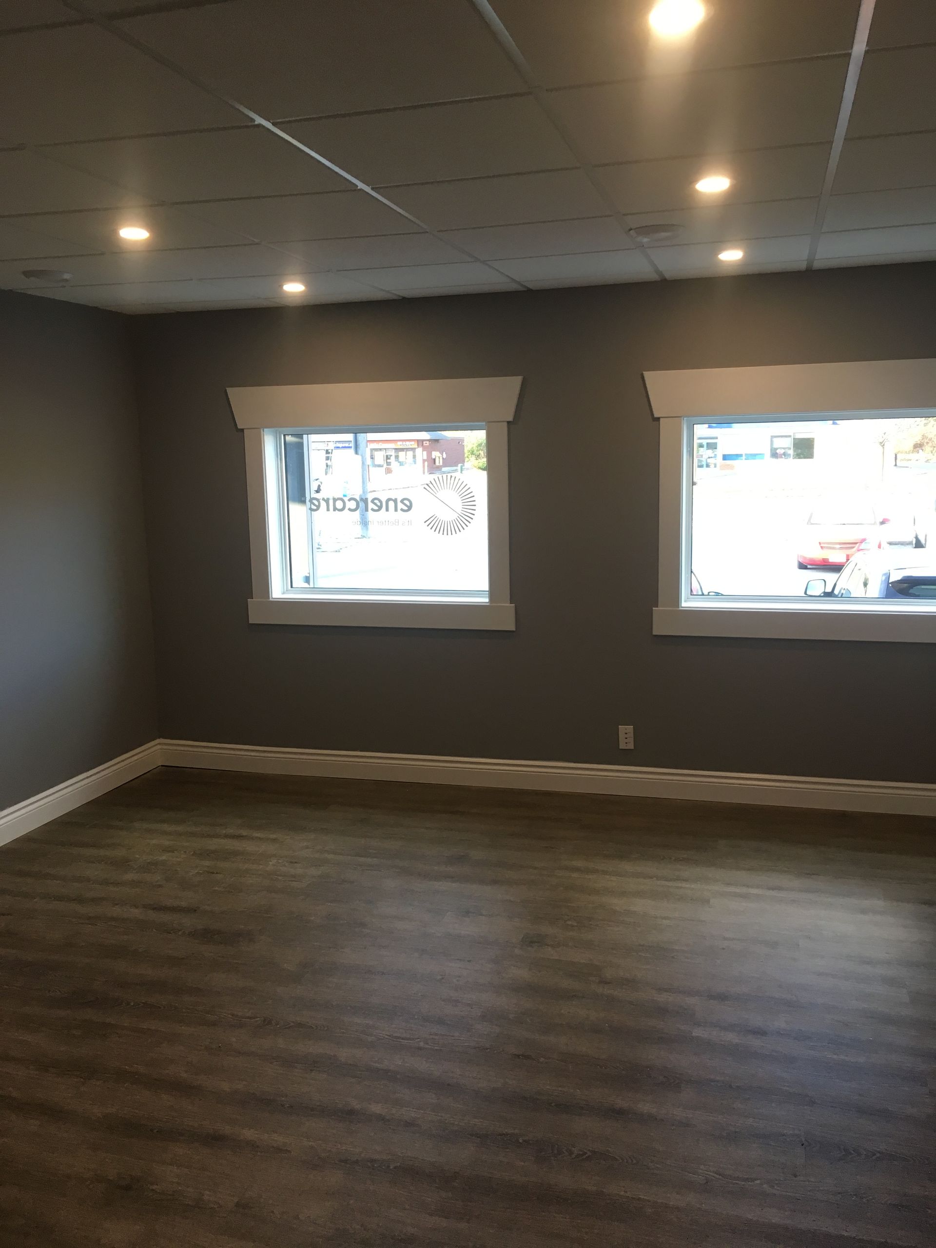 an empty room with two windows and a wooden floor