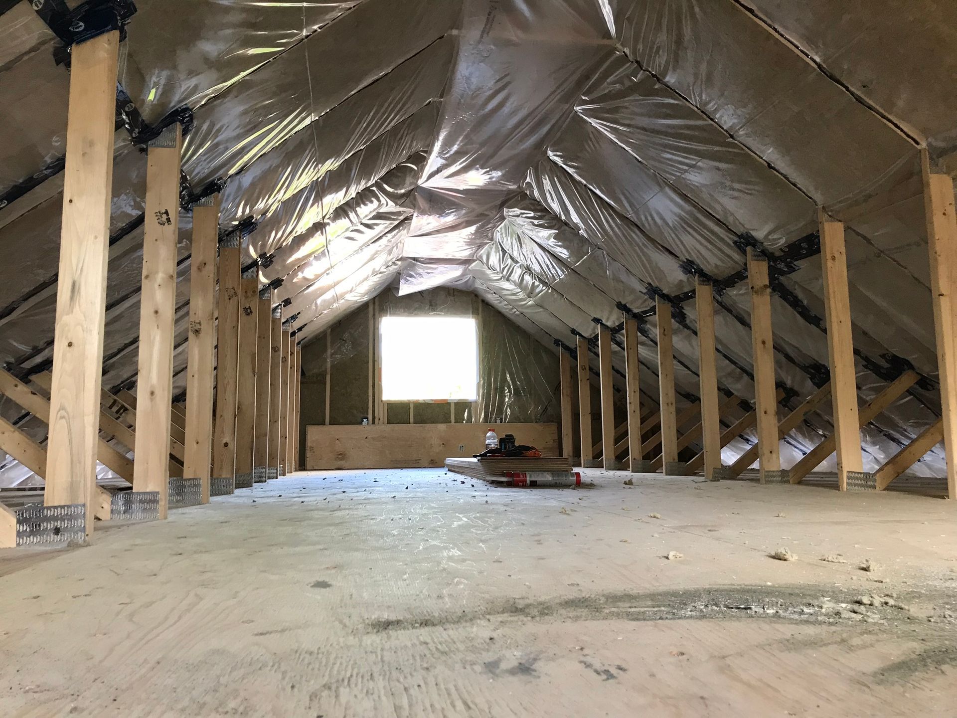 an empty attic with wooden beams and aluminum foil on the ceiling .