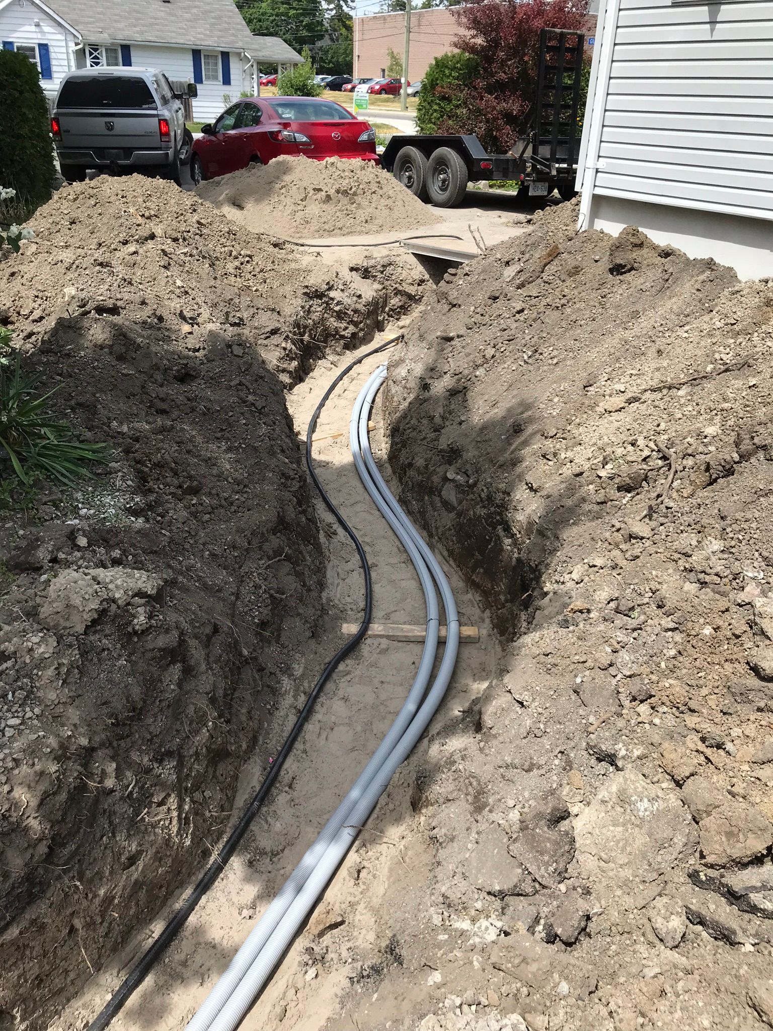 a bunch of pipes are being installed in the dirt in front of a house .