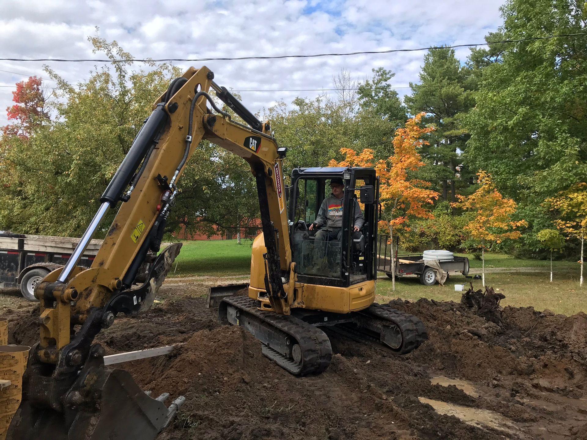 a man is driving a small excavator in a dirt field .