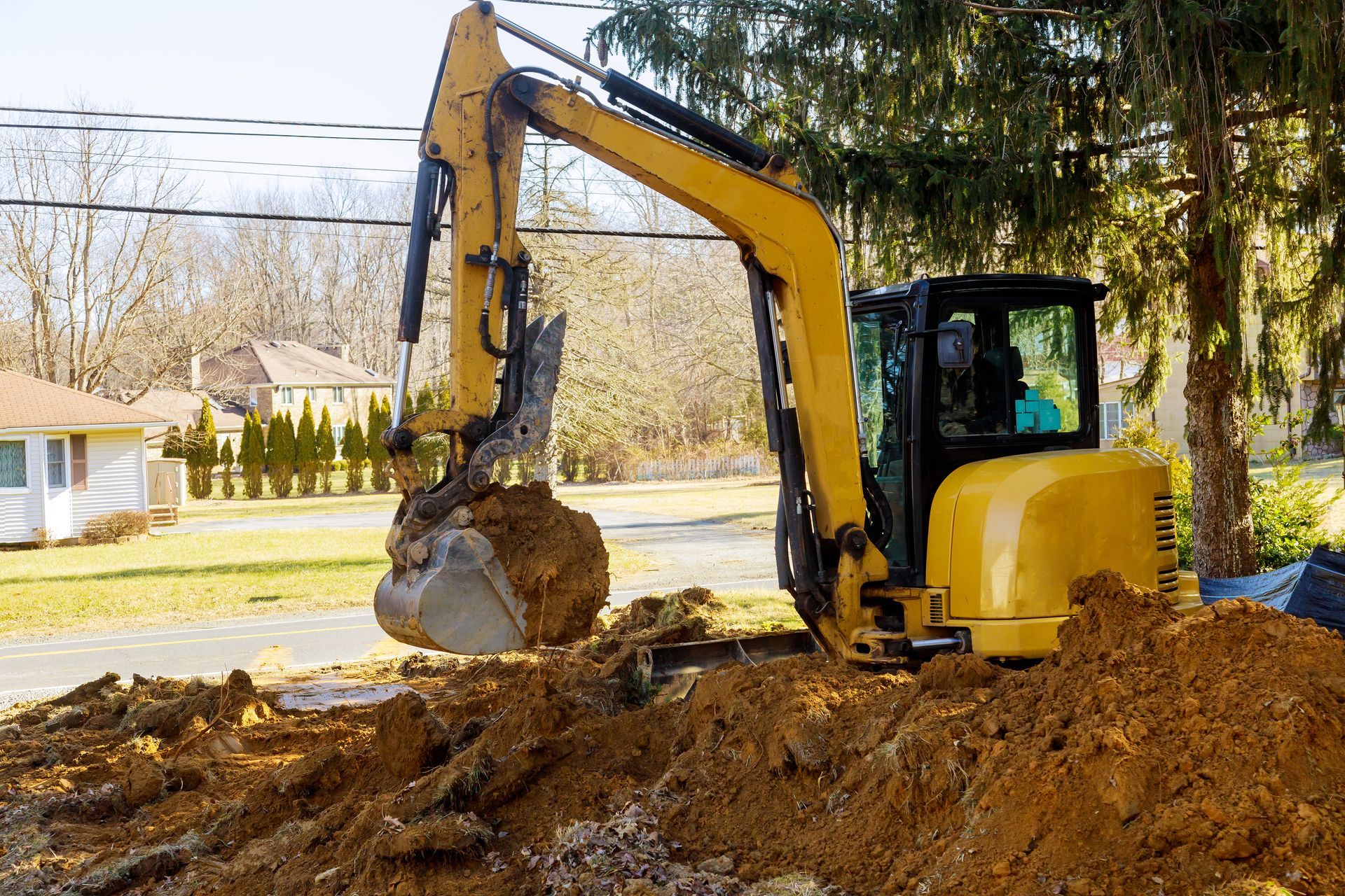 Yellow excavator digging in a residential yard.