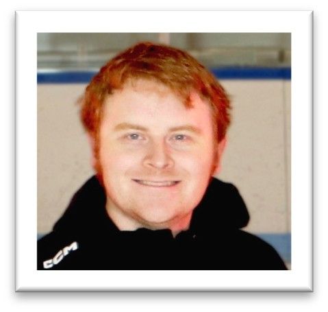 Portrait of a smiling person with short red hair wearing a black hoodie against a light background