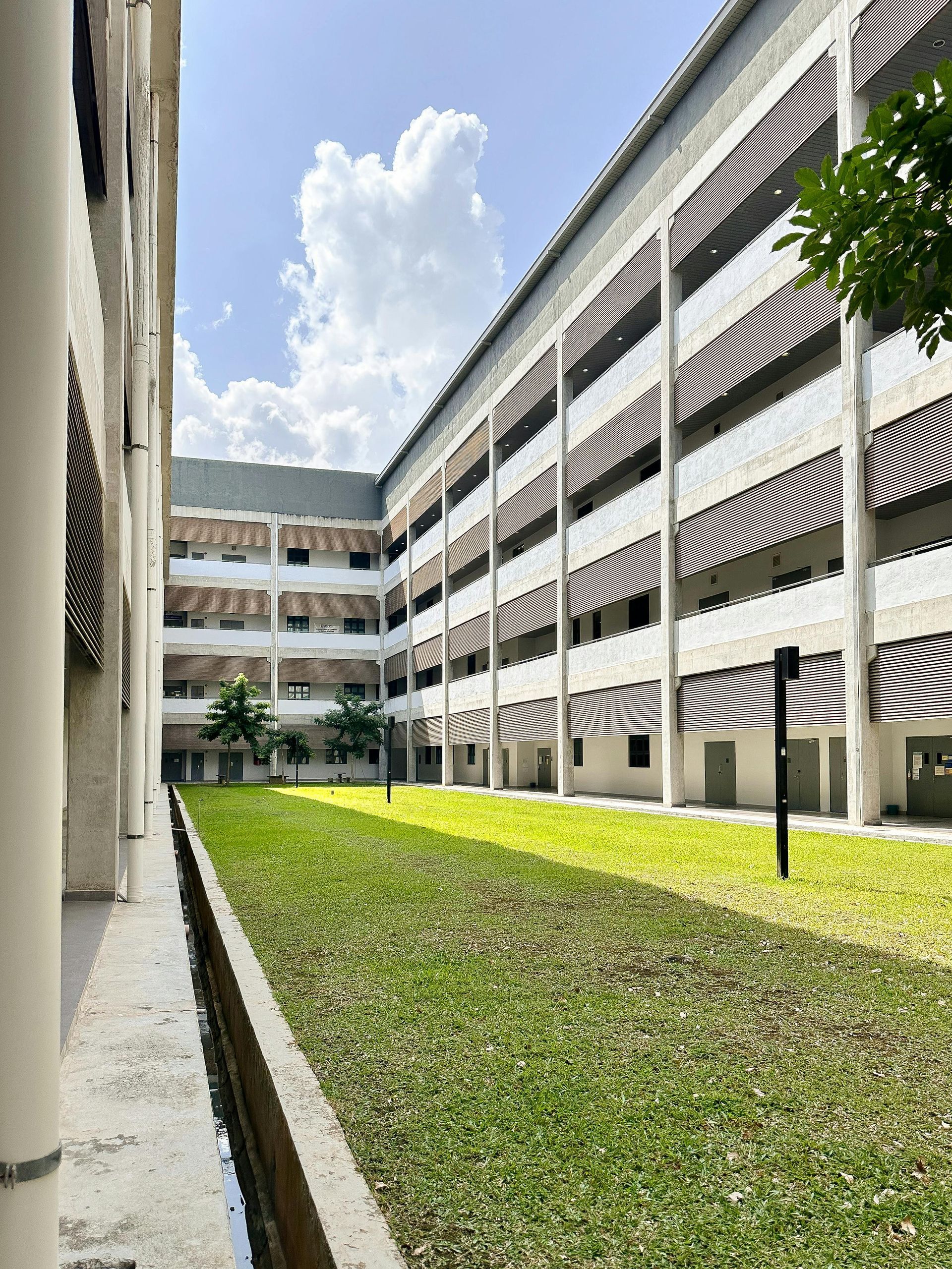 Courtyard between white apartment buildings with green grass and a bright sky