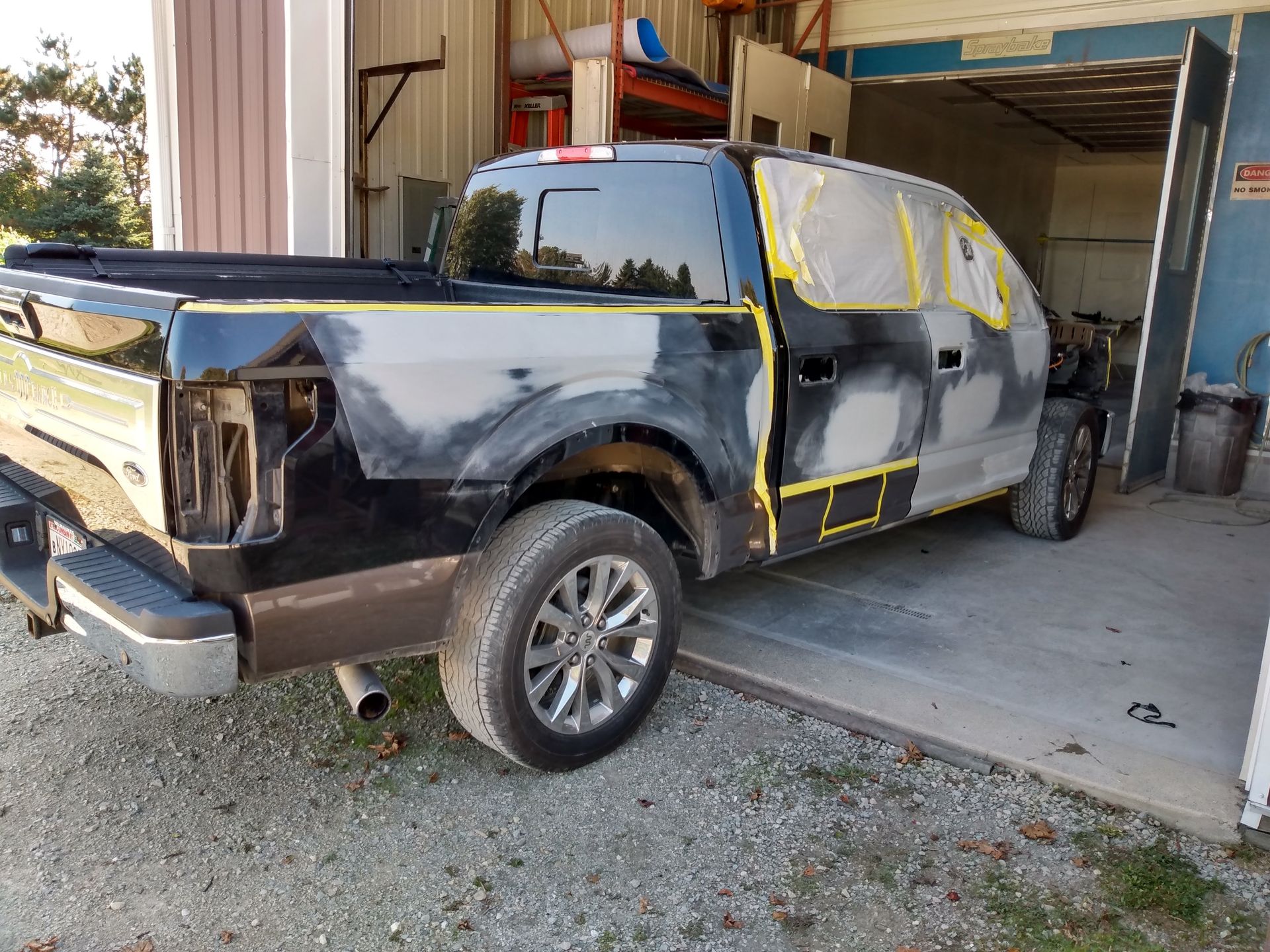 Black pickup truck with a partially repaired side panel in a garage workshop
